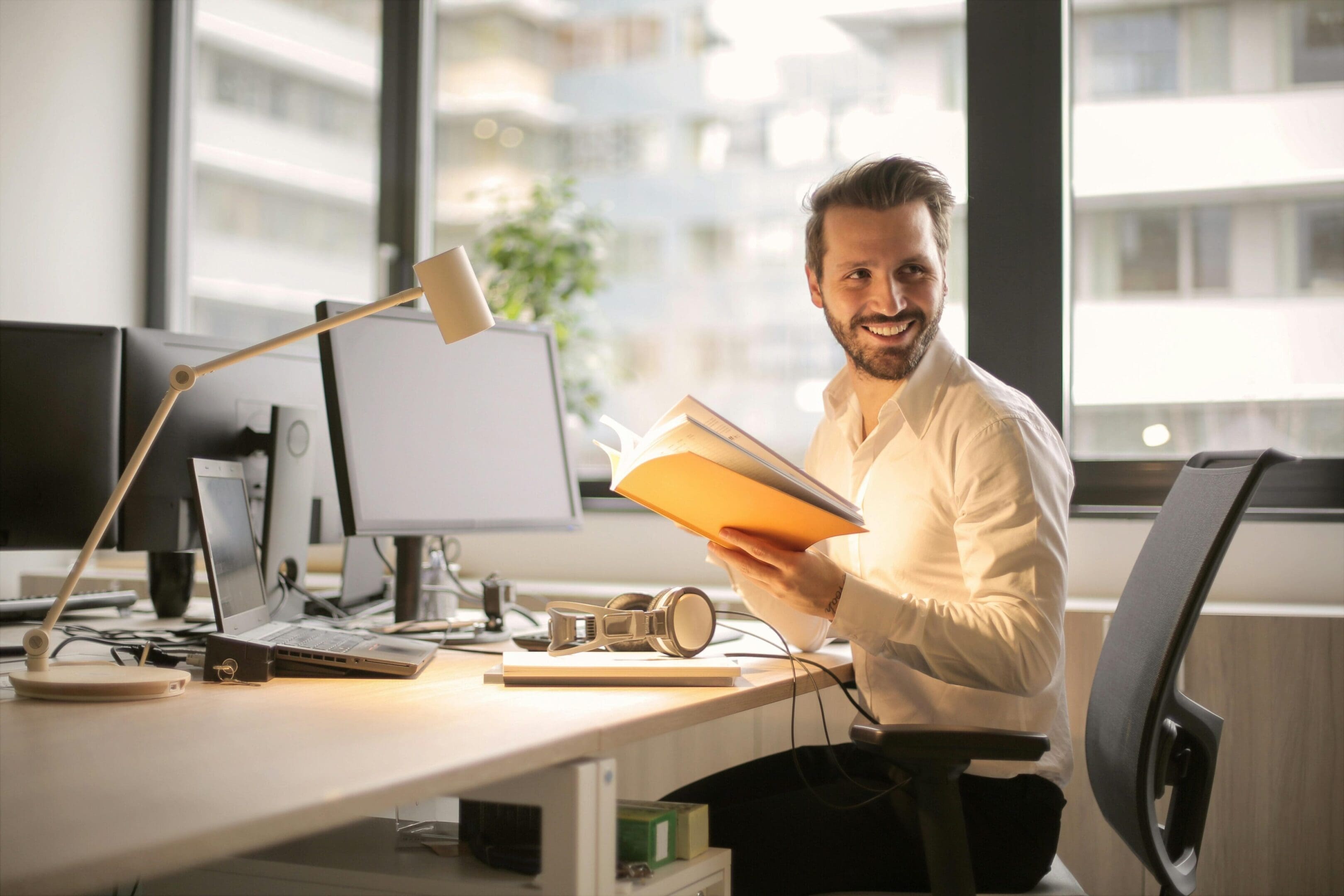 A man sitting at his desk reading a book.