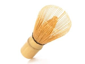 A wooden whisk is sitting on the table.